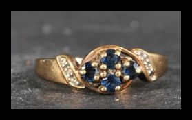 A hallmarked 9ct gold ring with central blue sapphire cluster and diamond accent shoulders. Weight
