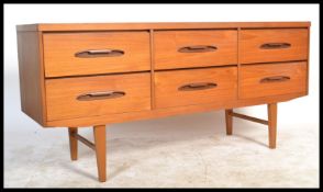 A retro 1970's teak wood sideboard being raised on turned tapering legs supporting a wide body