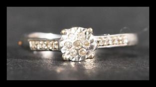A hallmarked 9ct gold and diamond cluster ring having diamond set shoulders. Hallmarked Sheffield.