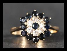 A hallmarked 9ct gold cluster ring having a central sapphire stone surrounded by halos of white