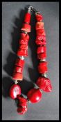 A large coral necklace of baroque form having large varying coral beads with silver white metal hook