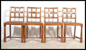 A set of four 20th Century Art Deco oak dining chairs, the chairs raised on turned legs united by