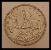 A 1935 silver crown coin in good condition. King George bust facing left with George and Dragon to