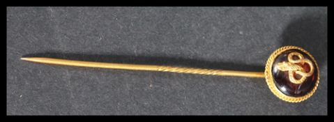 A yellow metal tests as 18ct gold stick pin brooch having an applied snake motif on red stone