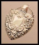 A sterling silver perfume bottle in the form of a heart having embossed decoration. Weighs 20.5
