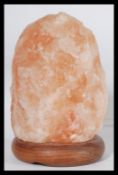 A retro Himalayan original 1970's salt crystal lamp in orange form being raised on an circular