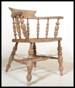 A Victorian beech and elm smokers bow armchair being raised on turned legs united by stretchers