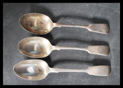 A group of three hallmarked silver table spoons in the fiddle pattern with reverse Hanoverian