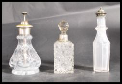 A group of three glass bottles one with white metal top , one an atomiser perfume bottle with yellow