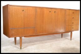 A retro 1970's teak wood sideboard being raised on shaped legs with a series of cupboards and