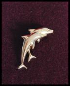 A vintage 9ct gold brooch in the form of two dolphins being stamped 375. Complete in presentation