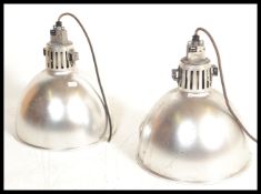A pair of vintage 20th century industrial factory ceiling lights having conical pendant shades.