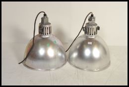A pair of vintage 20th century industrial factory ceiling lights having conical pendant shades.