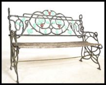 A vintage weathered garden bench having an ebonised cast iron back with painted leaf and vine