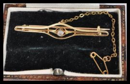 A vintage 20th century 9ct gold and single stone diamond bar brooch complete with safety chain in