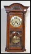 An early 20th century wooden cased wall wall clock having an astragal glazed door panel and arched