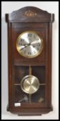 An early 20th century wooden cased wall wall clock having an astragal glazed door panel and arched