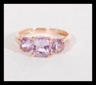 A hallmarked 9ct rose gold purple stone trilogy ri