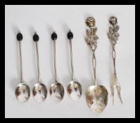 A group of four hallmarked silver coffee bean spoons along with a set pair of pickle fork and