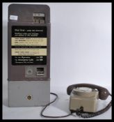 A vintage retro 20th century coin operated pay phone unit taking 5p and 10p coins attached to a