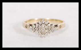 A hallmarked 9ct gold and diamond cluster ring with diamond set shoulders. Hallmarked London. Weight