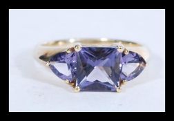 A hallmarked 9ct gold purple stone trilogy ring. H