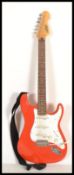A vintage six string electric guitar having a shaped red body with white scratch guard.