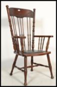 A 20th century American Windsor style country oak armchair raised on turned legs united by stretcher