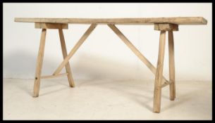 A vintage early 20th century rustic hand made industrial work bench raised on splayed legs with