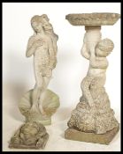 A group of vintage stone garden features to include a statue of a maiden stood on a open clam