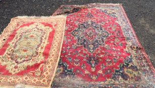 A pair of non matching vintage 20th Century floor rugs, the larger on red ground with central
