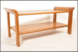 A 1970's retro vintage teak wood two tier coffee table having an inset glass to the top and raised