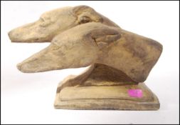 A stone cast of two hunting / racing / working dogs possibly Grey Hound heads on a stepped form.