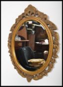 A vintage gilt surround oval wall mirror having an