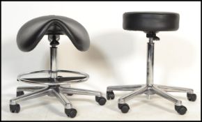 2 mid century surgeons / medical stools to include a saddle style stool with black vinyl seat and