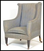 An Edwardian mahogany wingback Chesterfield style armchair being raised on square tapering legs with