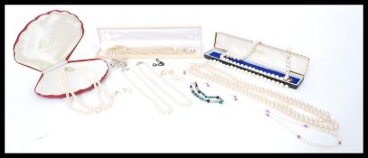 A group of faux and real pearl necklaces and jewellery mostly in boxes. brooches necklaces, earrings