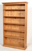 A tall antique style pine bookcase cabinet being raised on plinth base with a series of shelves