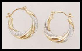 A pair of 9ct white and yellow gold hoop earrings having lever clasp fastenings. Marked 375 tests