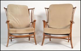A pair of 20th century armchairs in the manner of Ercol. Each with loose cushions to seat and back