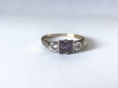 A hallmarked 9ct gold three stone ring set with a central amethyst flanked by white stones.