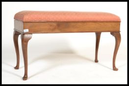 A 1930's walnut duet piano stool being raised on cabriole legs with pad feet supporting a wide