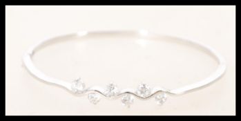 A silver bangle with cubic zirconia in prong settings. The bracelet is 5.6cm wide and includes a