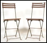 A pair of vintage retro 20th century metal folding lawn bistro chairs having slatted wooden seats.