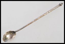 A 19th century large silver white metal mote spoon having an engraved stem with scalloped bowl.