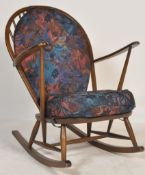 A mid 20th century Ercol beech and elm wood Windsor pattern large rocking chair being  raised on