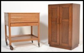A 1940's post war golden oak sewing box trolley. Raised on castors with square legs having hinged