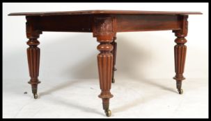 A Victorian mahogany extending dining table being raised on good reeded baluster legs with brass