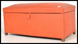 A vintage retro 20th century orange ottoman blanket box finished in a vibrant orange leatherette.