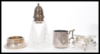 A group of four silver condiment items to include a cut glass silver lidded pepperette, silver